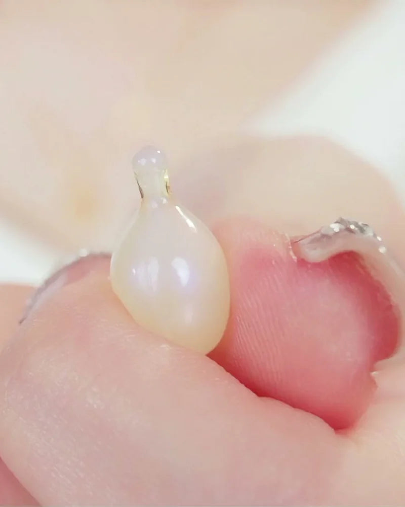 Fingers squeezing the serum out of one twisted-open capsule